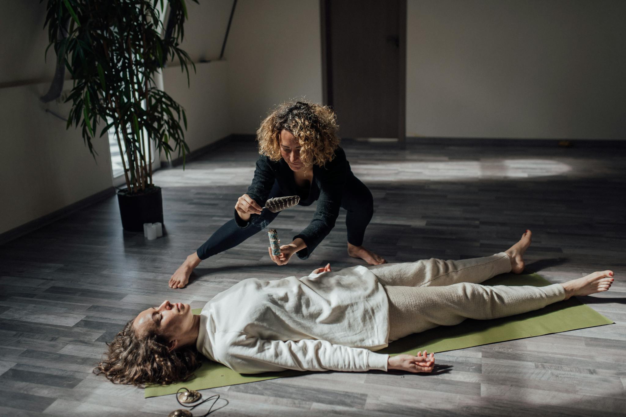 A reiki healer uses white sage in a calming indoor setting for a spiritual healing ritual.